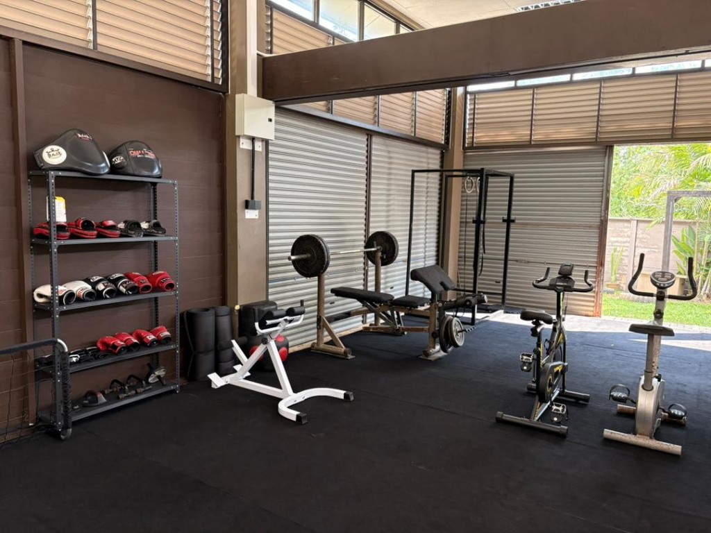 Squat rack, bench press, spin bikes, and Muay Thai gloves wall at Bambu