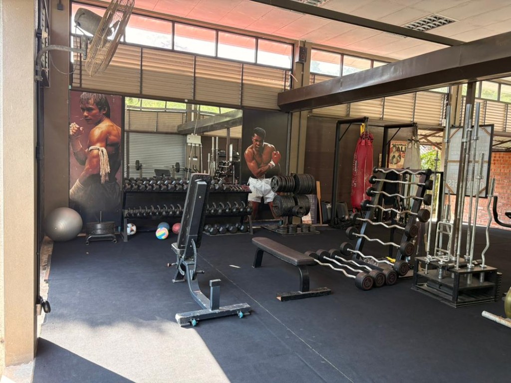 Bambu free-weights area with full dumbbell rack and Muay Thai and Muhammad Ali murals