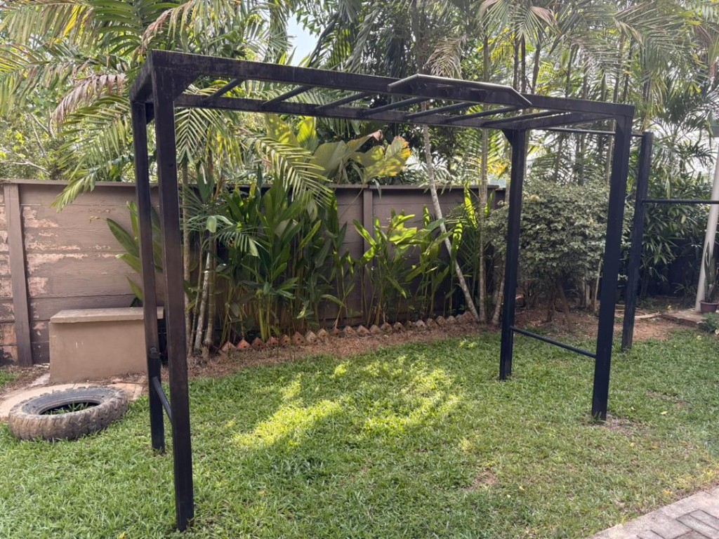 Outdoor calisthenics pull-up rig in the Bambu garden surrounded by palms