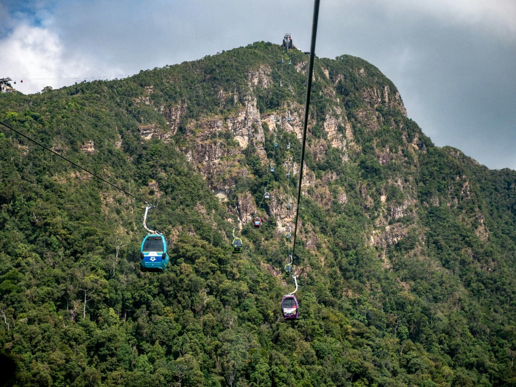 Colourful Langkawi SkyCab gondolas climbing steep jungle-covered slopes toward the summit